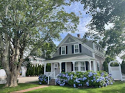 white and gray wooden house near green trees under white clouds during daytime