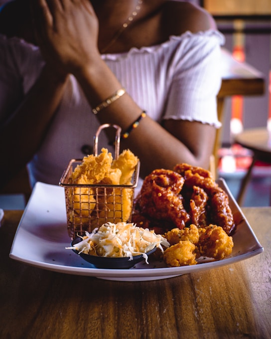 Woman sitting at a table with fried food, representing real life cravings and mindful choices
