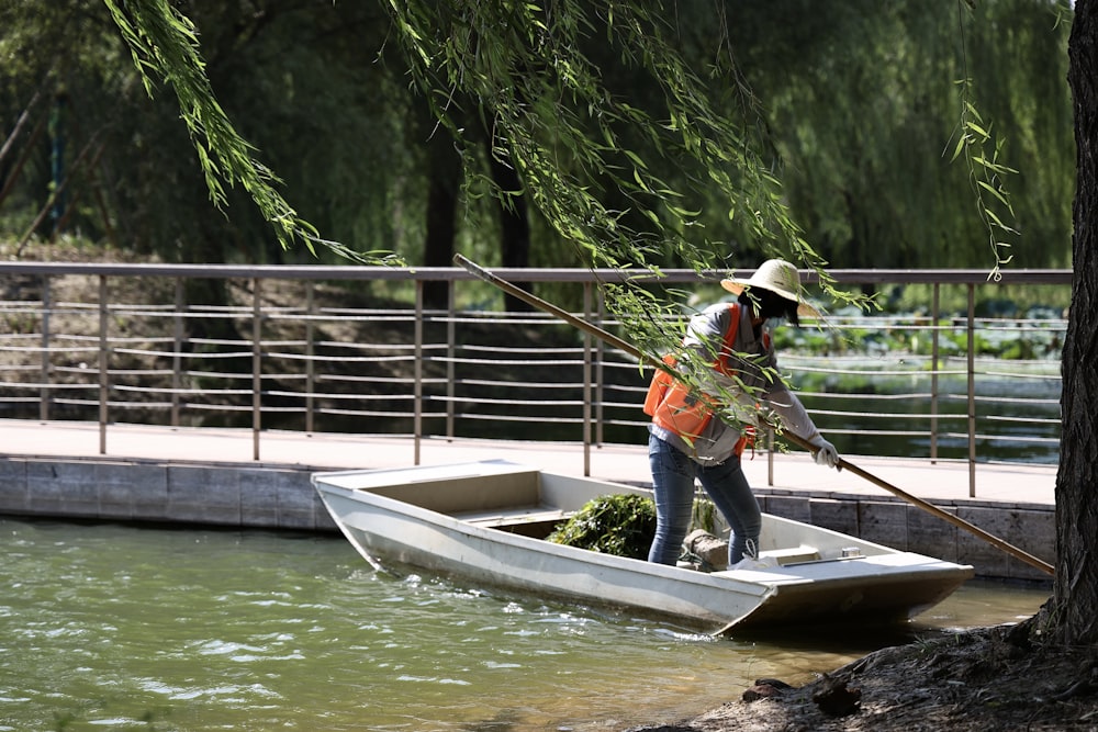 man in orange jacket and blue denim jeans standing on white boat during daytime