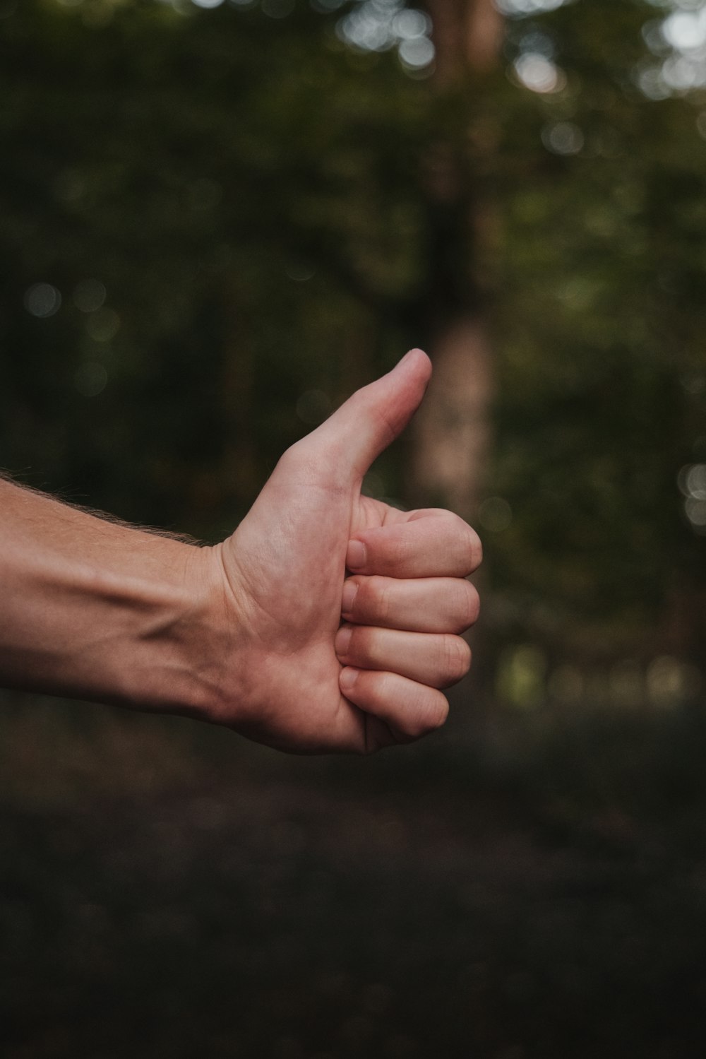 persons right hand doing thumbs up