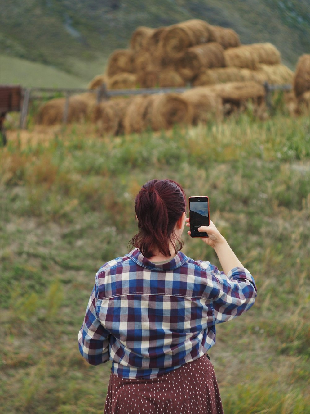 woman in blue and white plaid dress shirt holding black smartphone