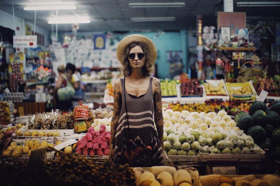 woman in brown and white tank top standing in front of fruit stand