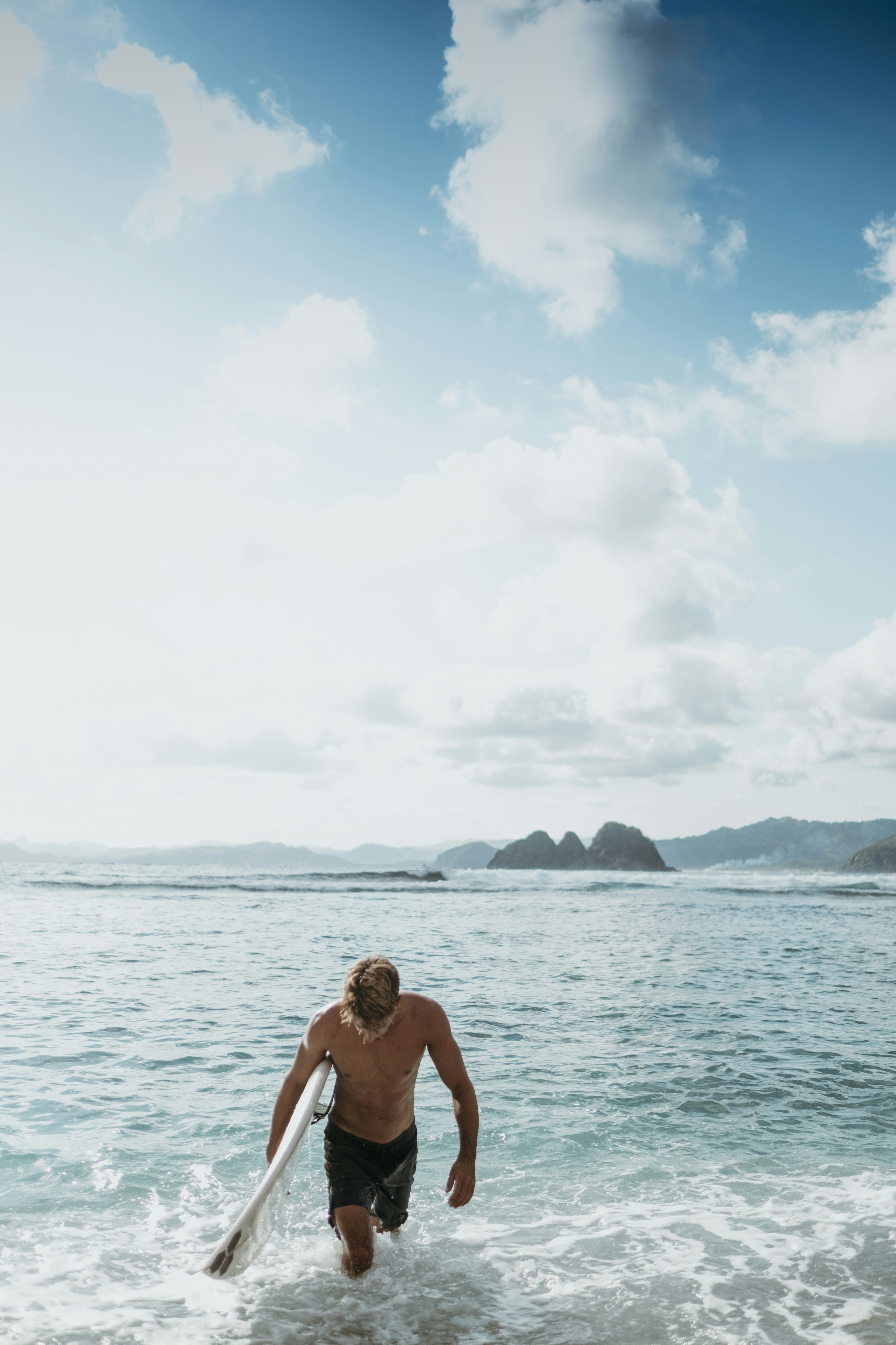 topless man sitting on the beach during daytime