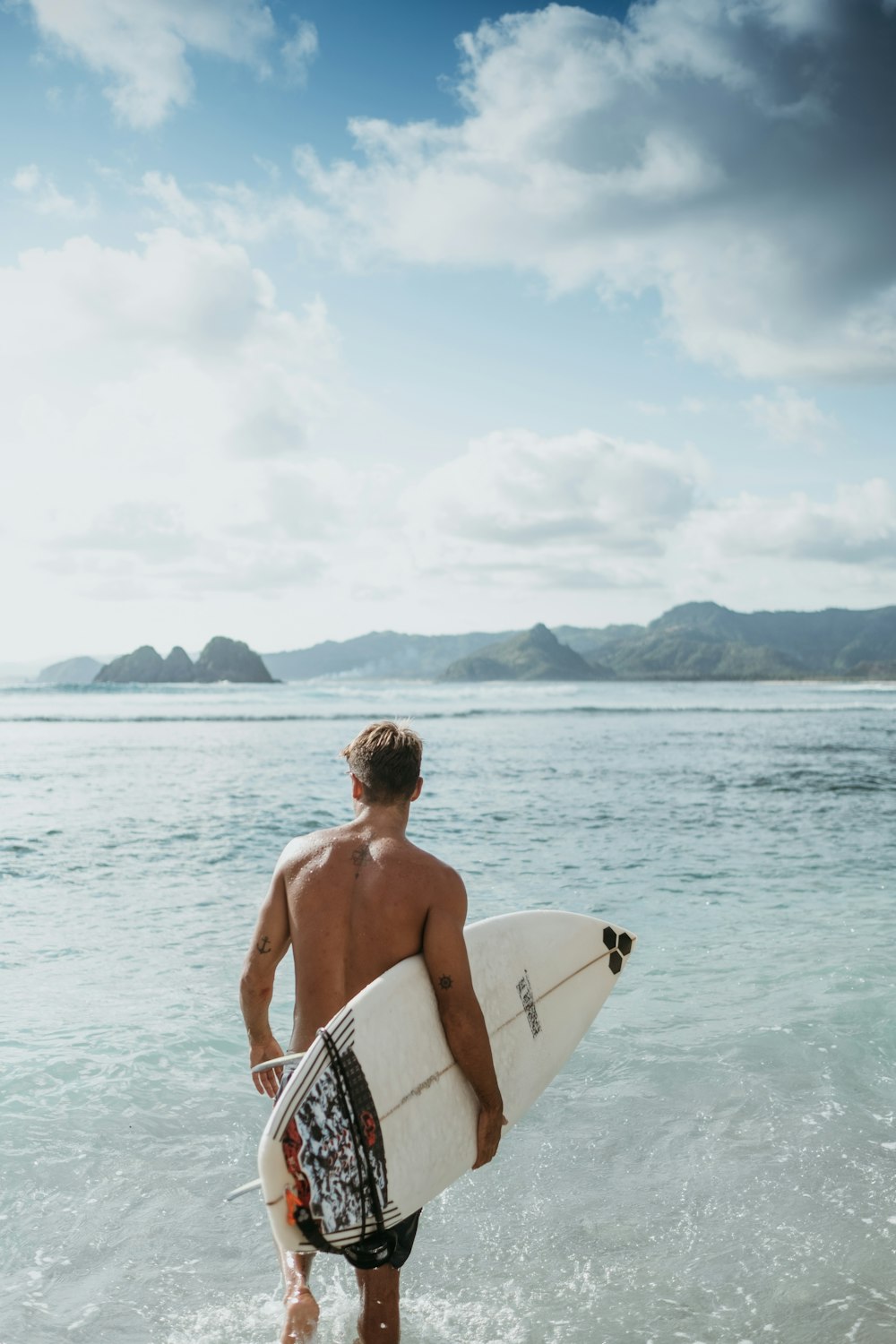 uomo in tavola da surf bianca e nera sul mare durante il giorno