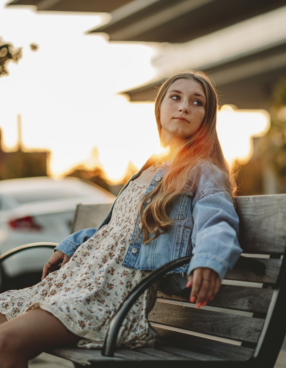 woman in blue denim jacket sitting on brown wooden bench during daytime