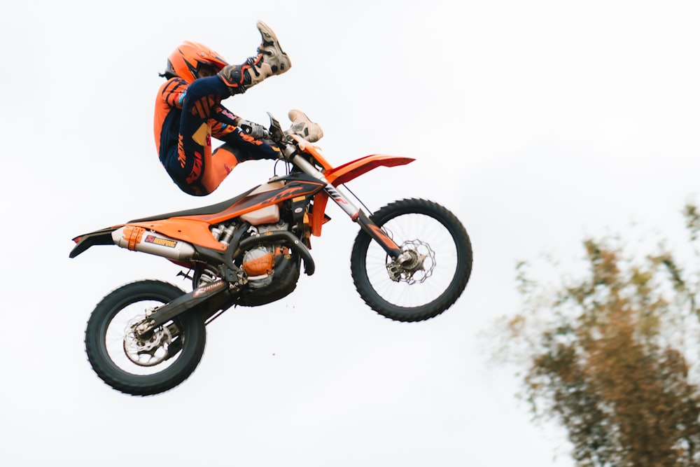 man in orange jacket riding motocross dirt bike