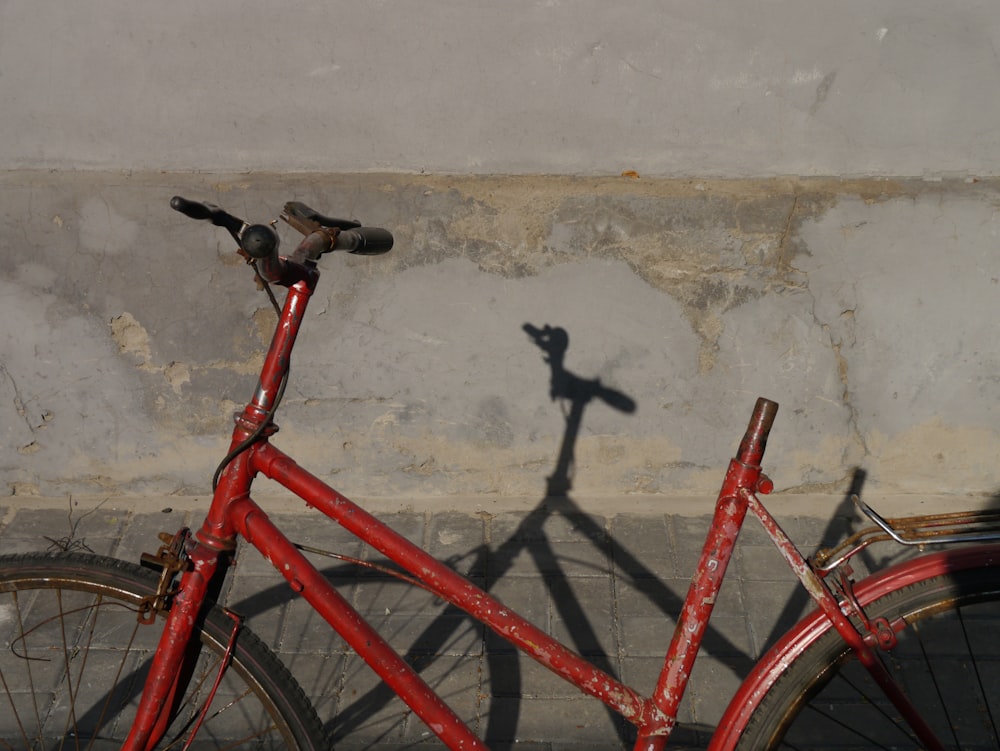 red and black bicycle leaning on wall