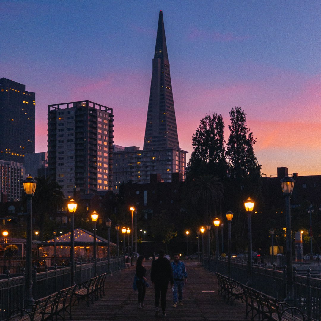 people walking on sidewalk near high rise building during night time