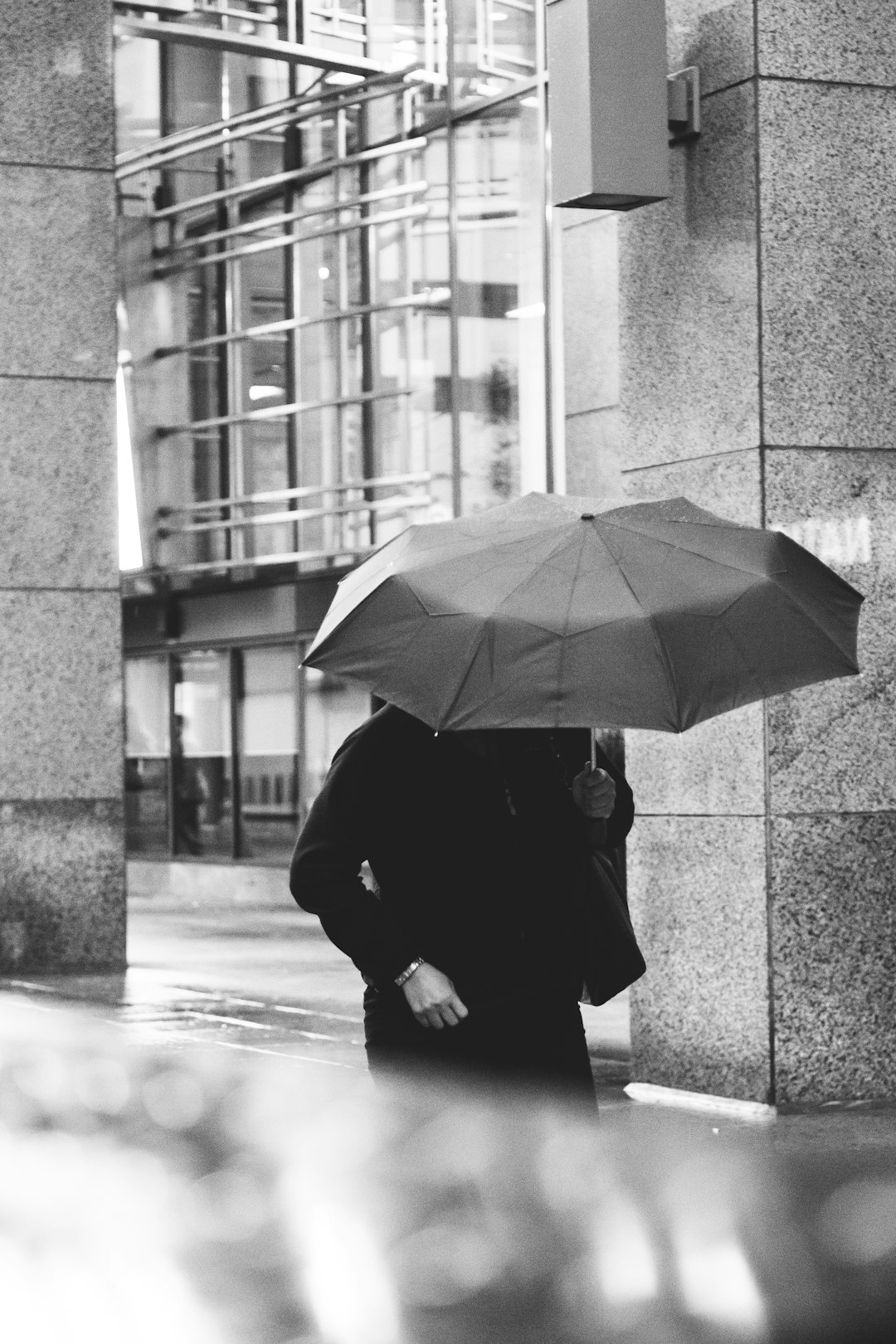 person in black coat holding umbrella walking on sidewalk during daytime