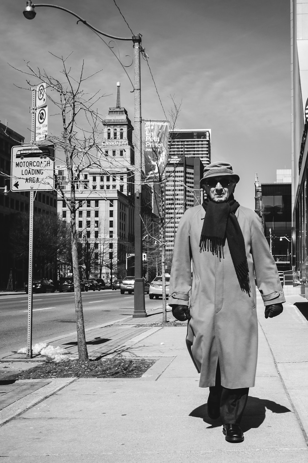 grayscale photo of man in jacket and helmet standing on sidewalk