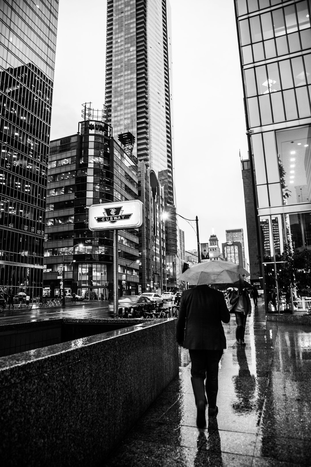 grayscale photo of person walking on sidewalk