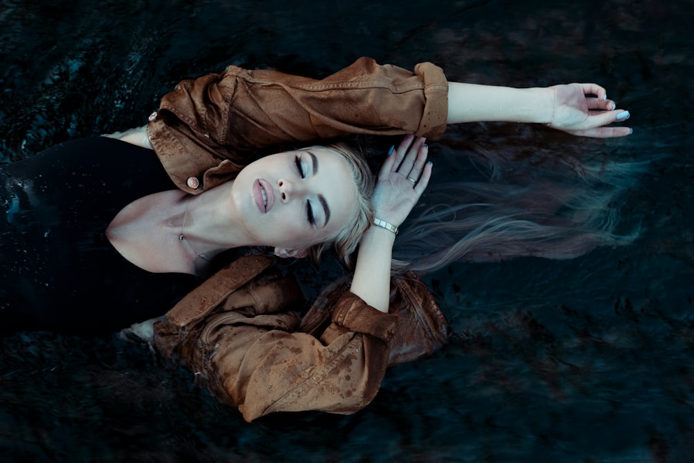 woman in brown coat lying on water
