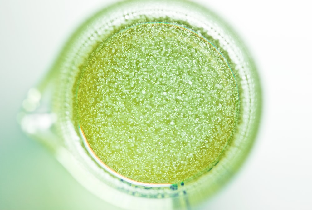 백색 세라믹 컵에 있는 녹색 액체