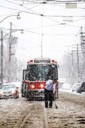 person in black jacket standing near red and black tram during daytime