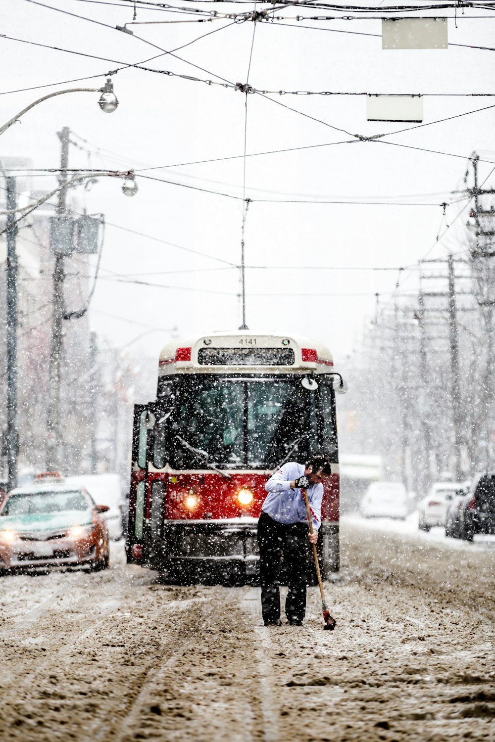 person in black jacket standing near red and black tram during daytime