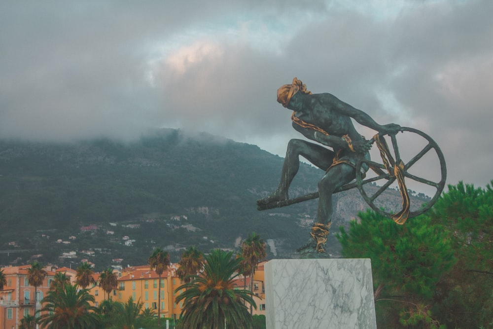 man riding bicycle statue on top of building