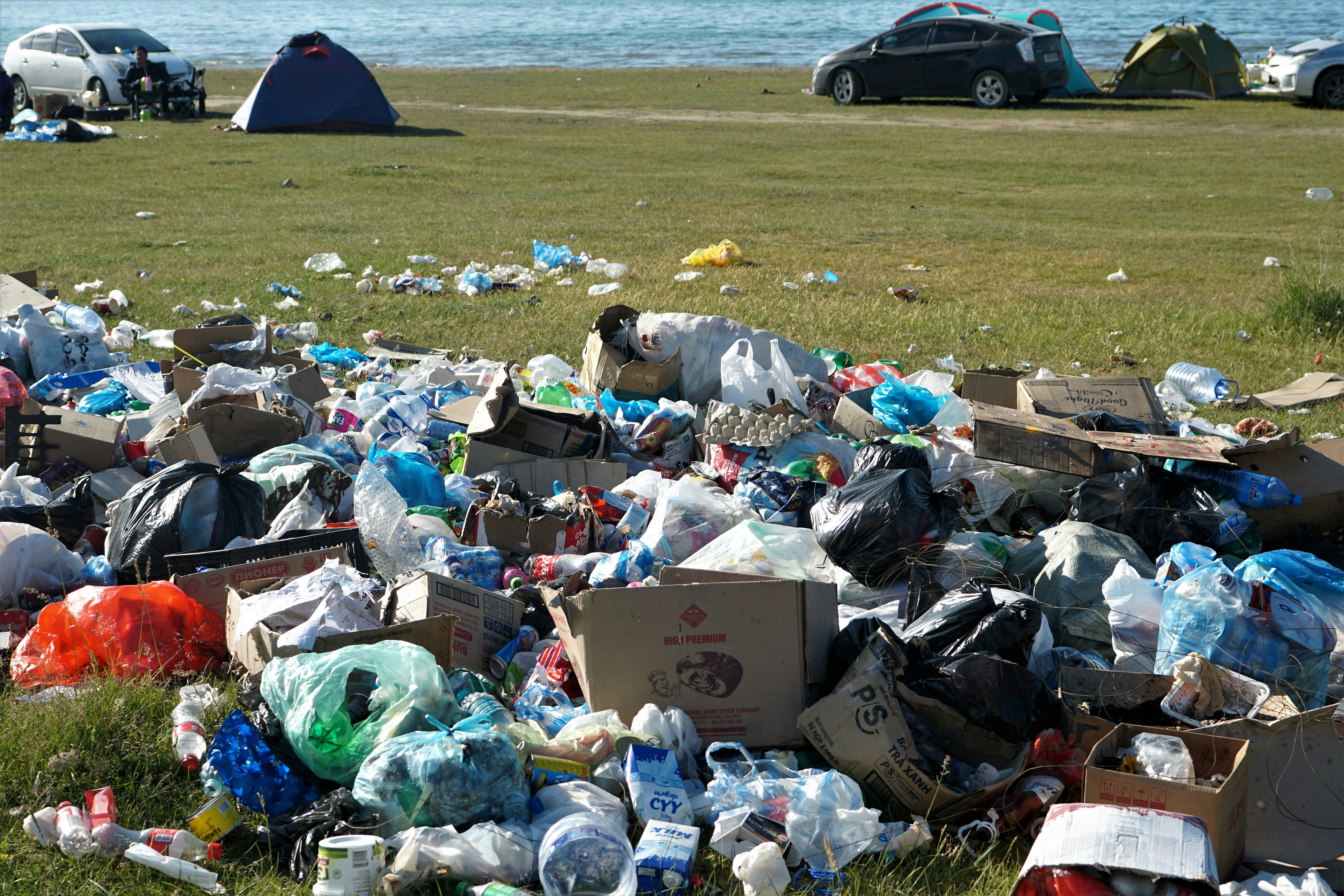 garbage bags on green grass field near body of water during daytime