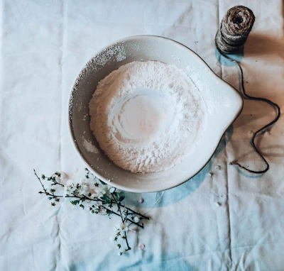 A bowl filled with white soap powder surrounded by clean laundry