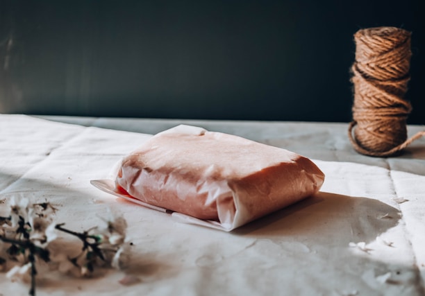 Close-up of hands unboxing a neatly wrapped product on a wooden table.