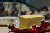 Fresh butter blocks displayed alongside packaged biscuits in a bright store setting.