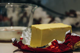 Fresh butter blocks displayed alongside packaged biscuits in a bright store setting.