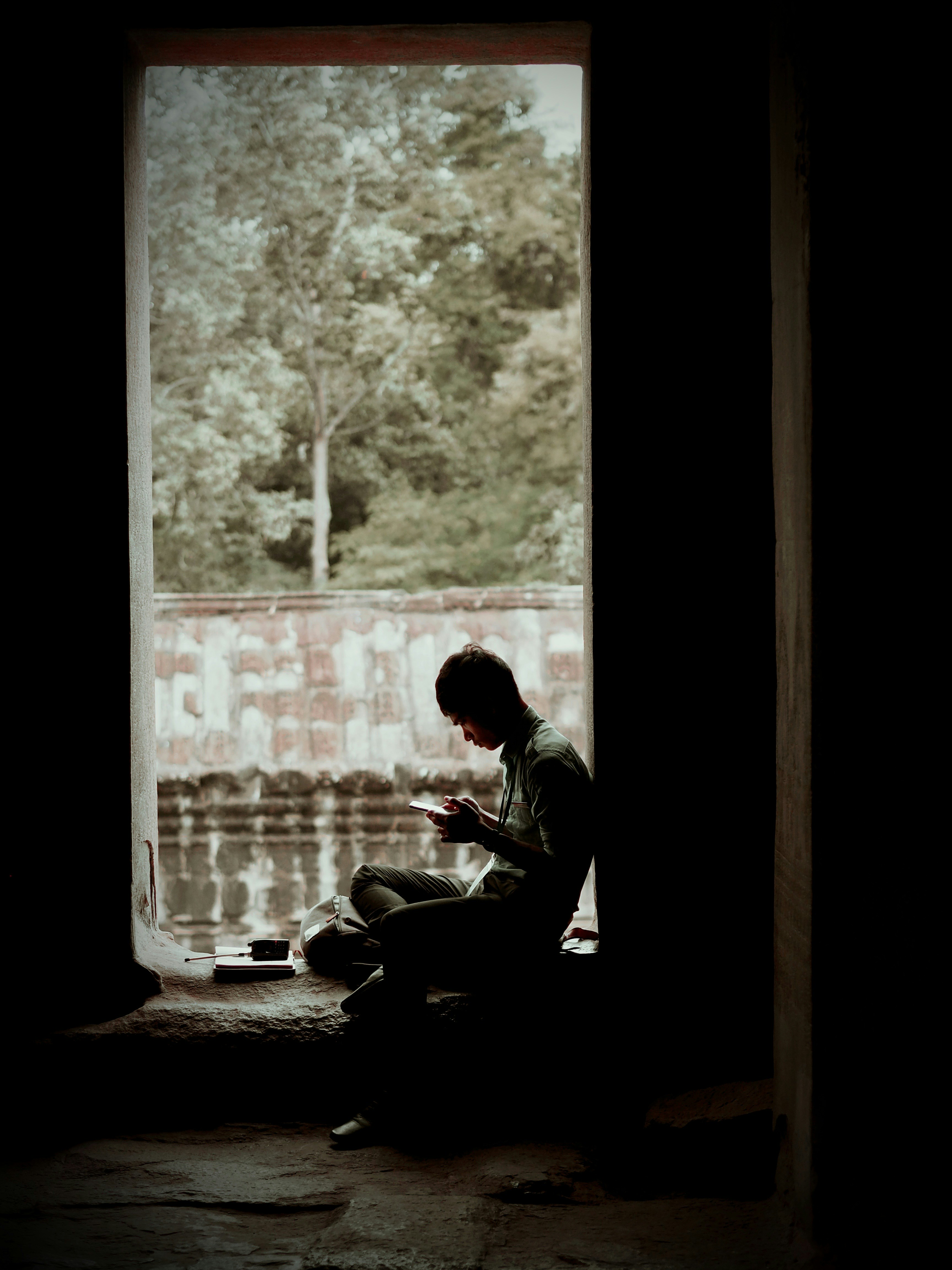 man in black jacket sitting on chair near window during daytime