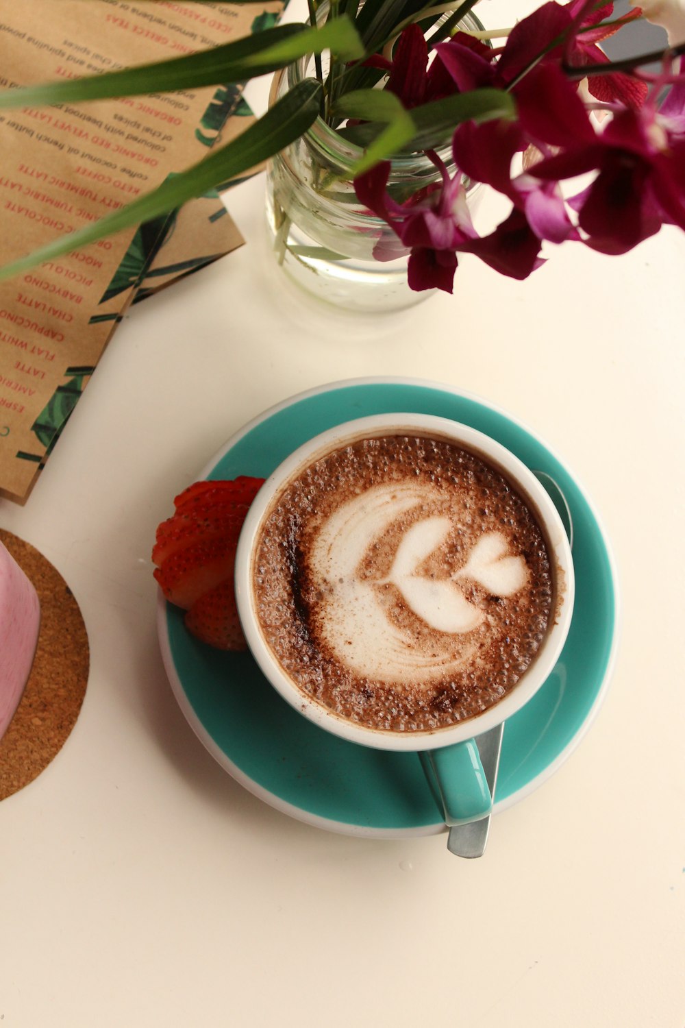 brown and white heart shaped coffee on teal ceramic mug