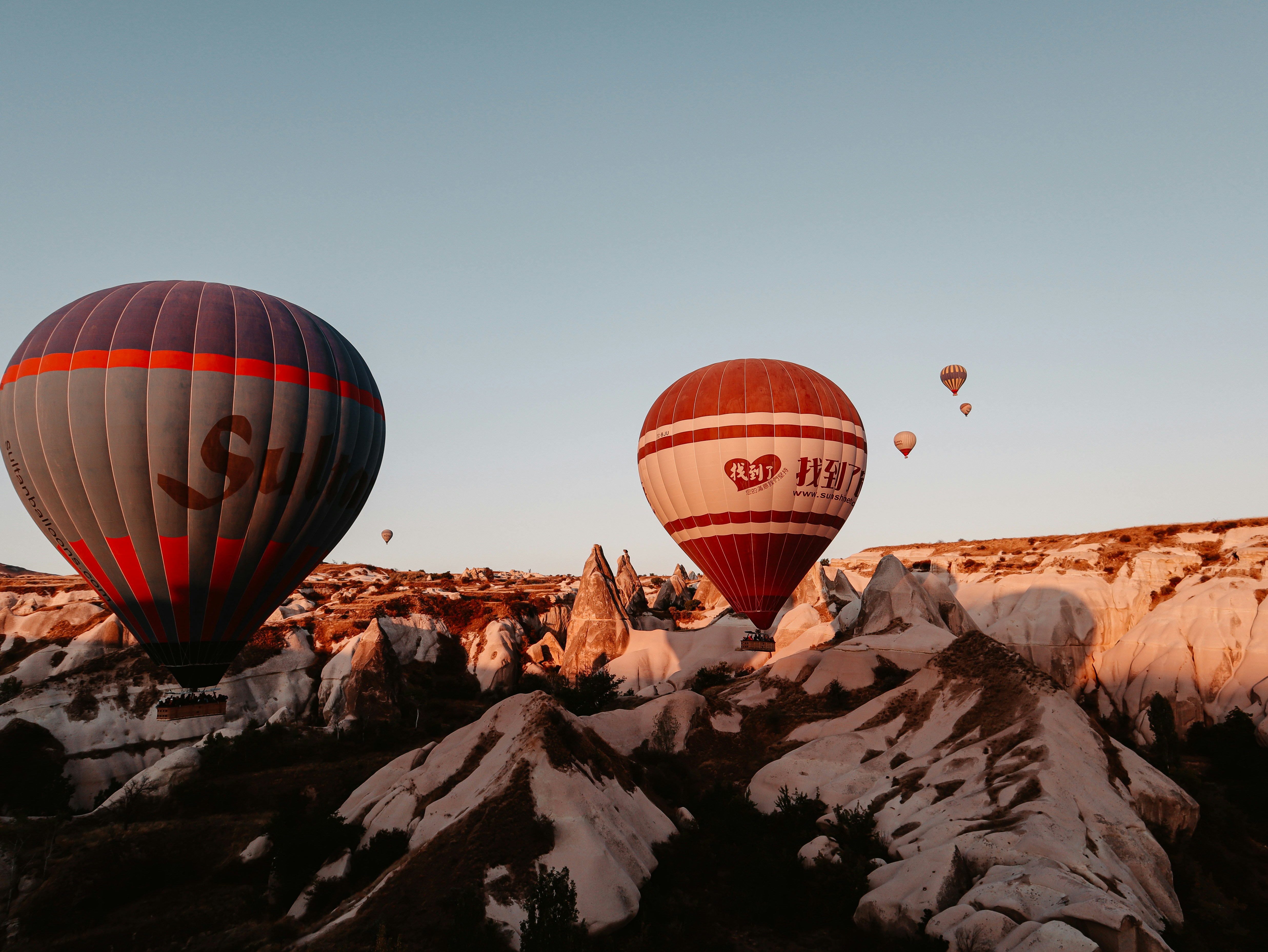 Balon udara merah dan hitam terbang di atas gunung