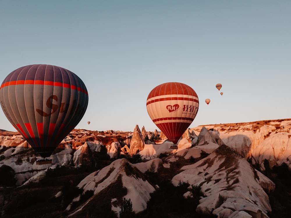 Roter und schwarzer Heißluftballon fliegt über den Berg