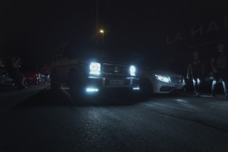 Nighttime shot of a luxury car rally with glowing orange accents illuminating the scene.