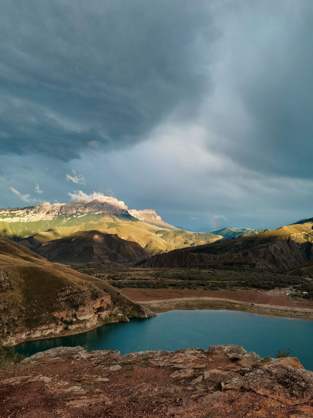 lake in the middle of mountains under blue sky and white clouds during daytime