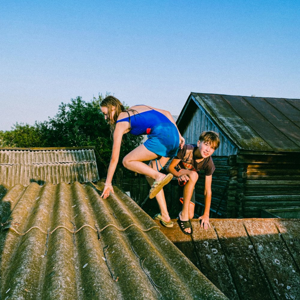 woman in blue t-shirt and brown shorts sitting on brown wooden dock during daytime