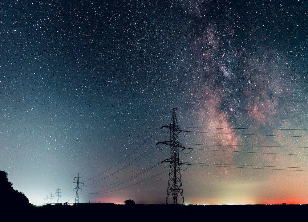 silhouette of electric post under starry night