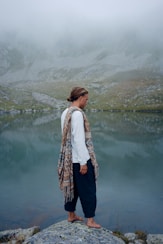 woman in white long sleeve shirt and black pants standing near lake during daytime