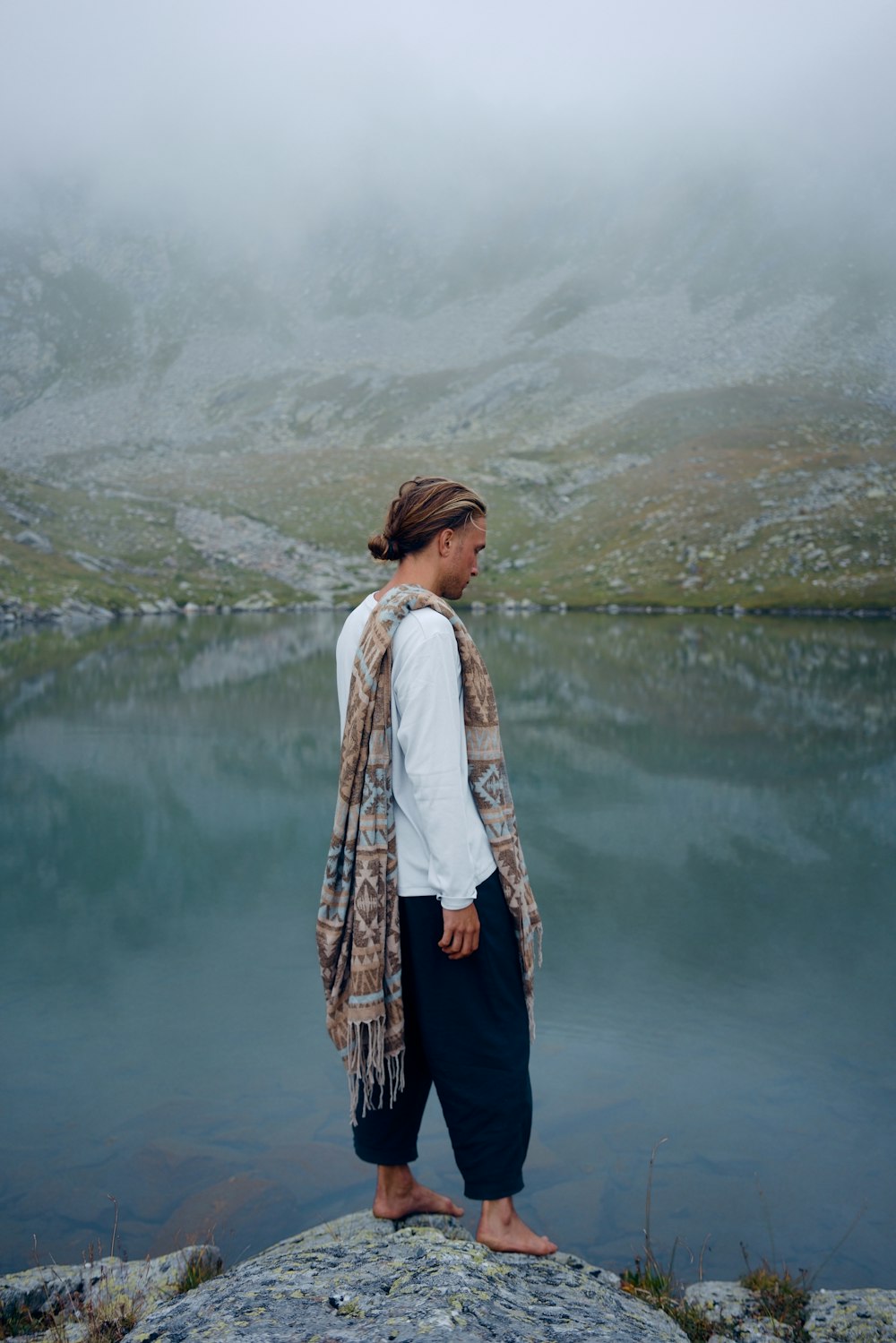 woman in white long sleeve shirt and black pants standing near lake during daytime