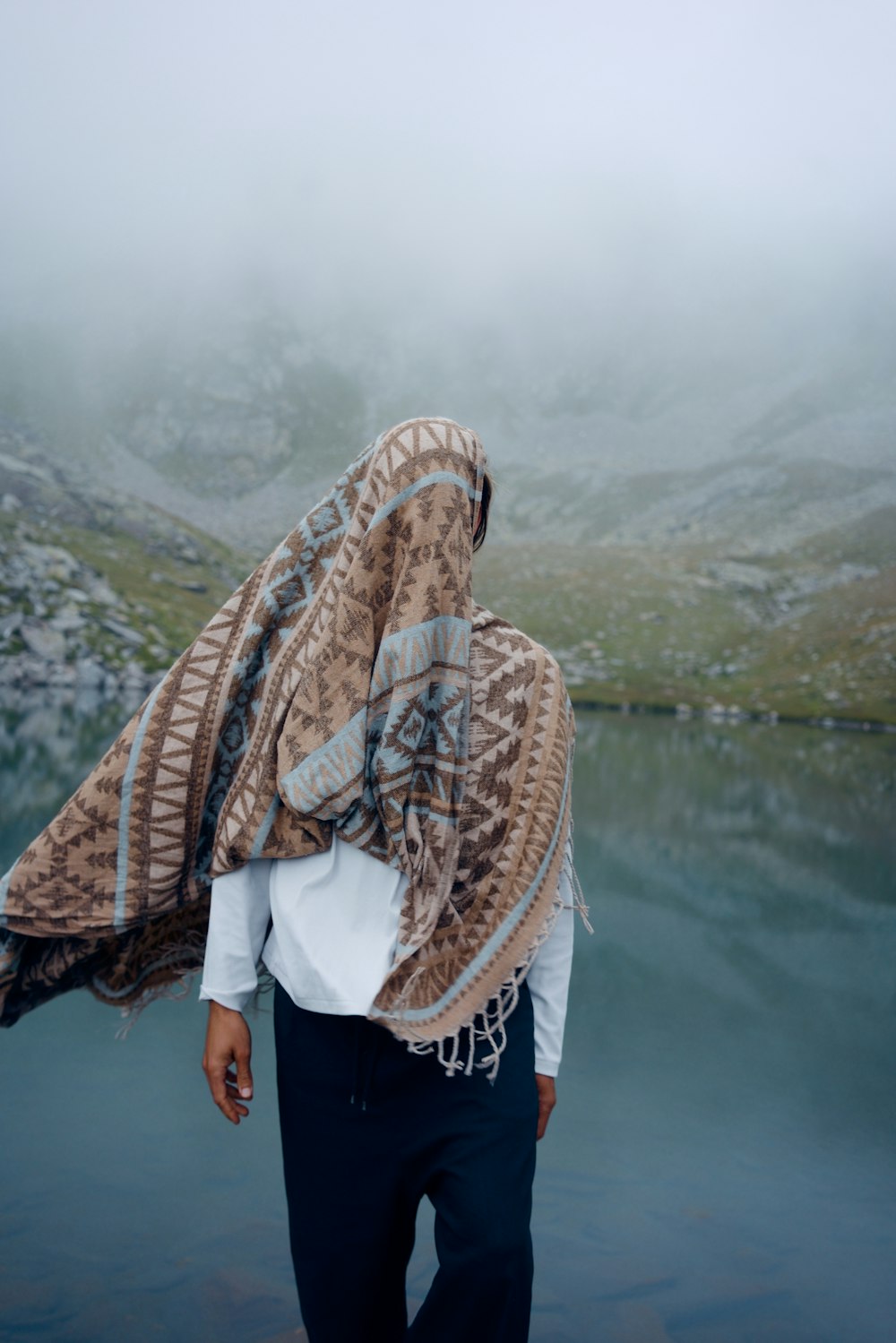 woman in white shirt and brown scarf standing near lake during daytime