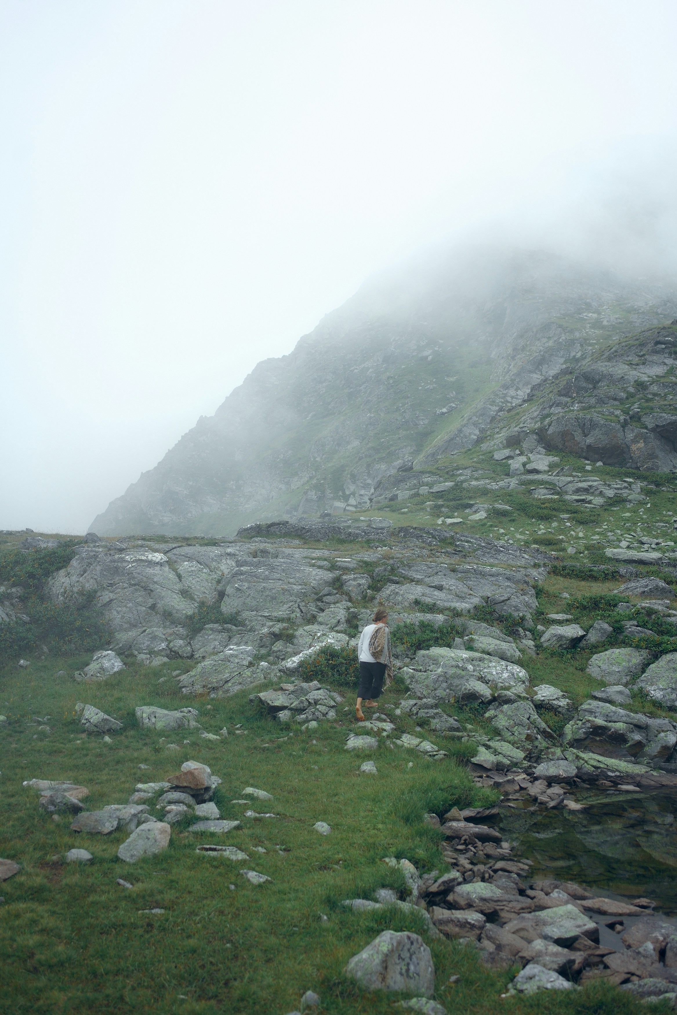 man in white t-shirt walking on green grass field during daytime