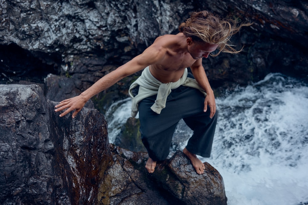 woman in white tank top and black pants sitting on rock