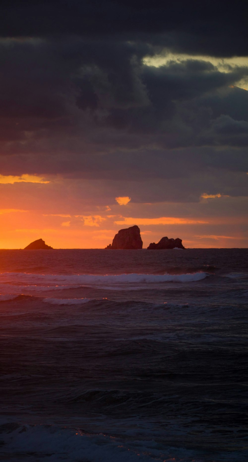 brown rock formation on sea during sunset