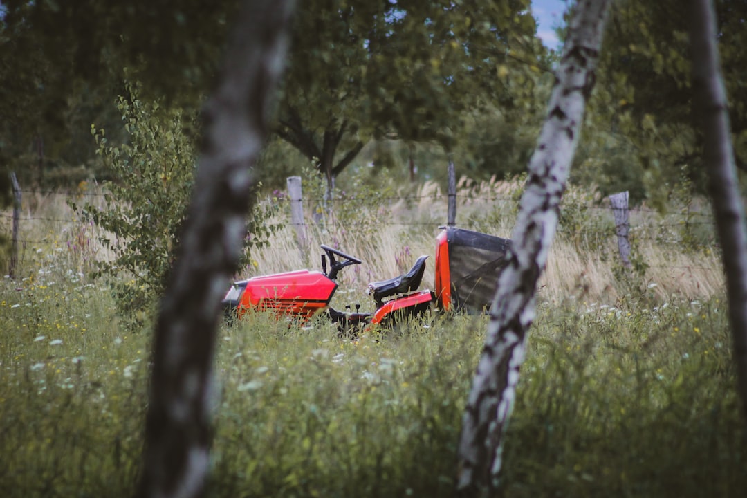 red and black tractor on green grass field during daytime