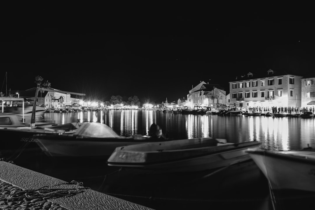 grayscale photo of boat on water near building