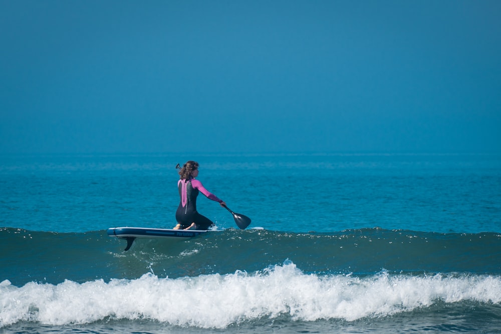 woman in black wetsuit surfing on sea waves during daytime