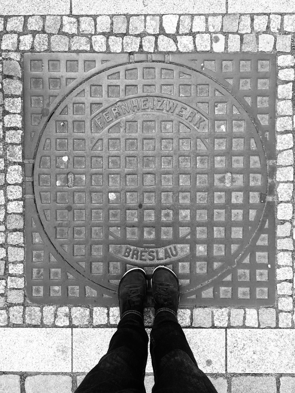 person in black pants and black shoes standing on gray round metal