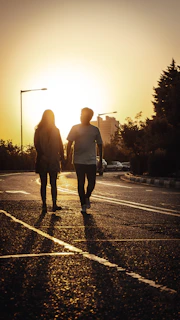A couple walking hand in hand at sunset, representing choosing a shared path in life.