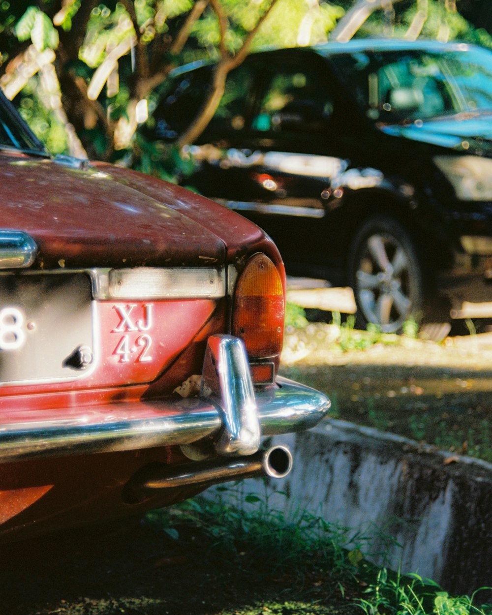 red mercedes benz car parked beside black car during daytime