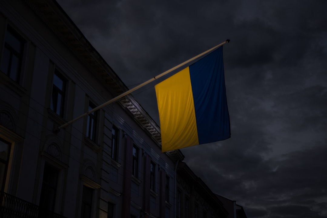 Ukraine independence day dramatic concept photography of Ukrainian flag yellow and blue color near government building on cloudy and stormy sky background symbolism of hard times in European country