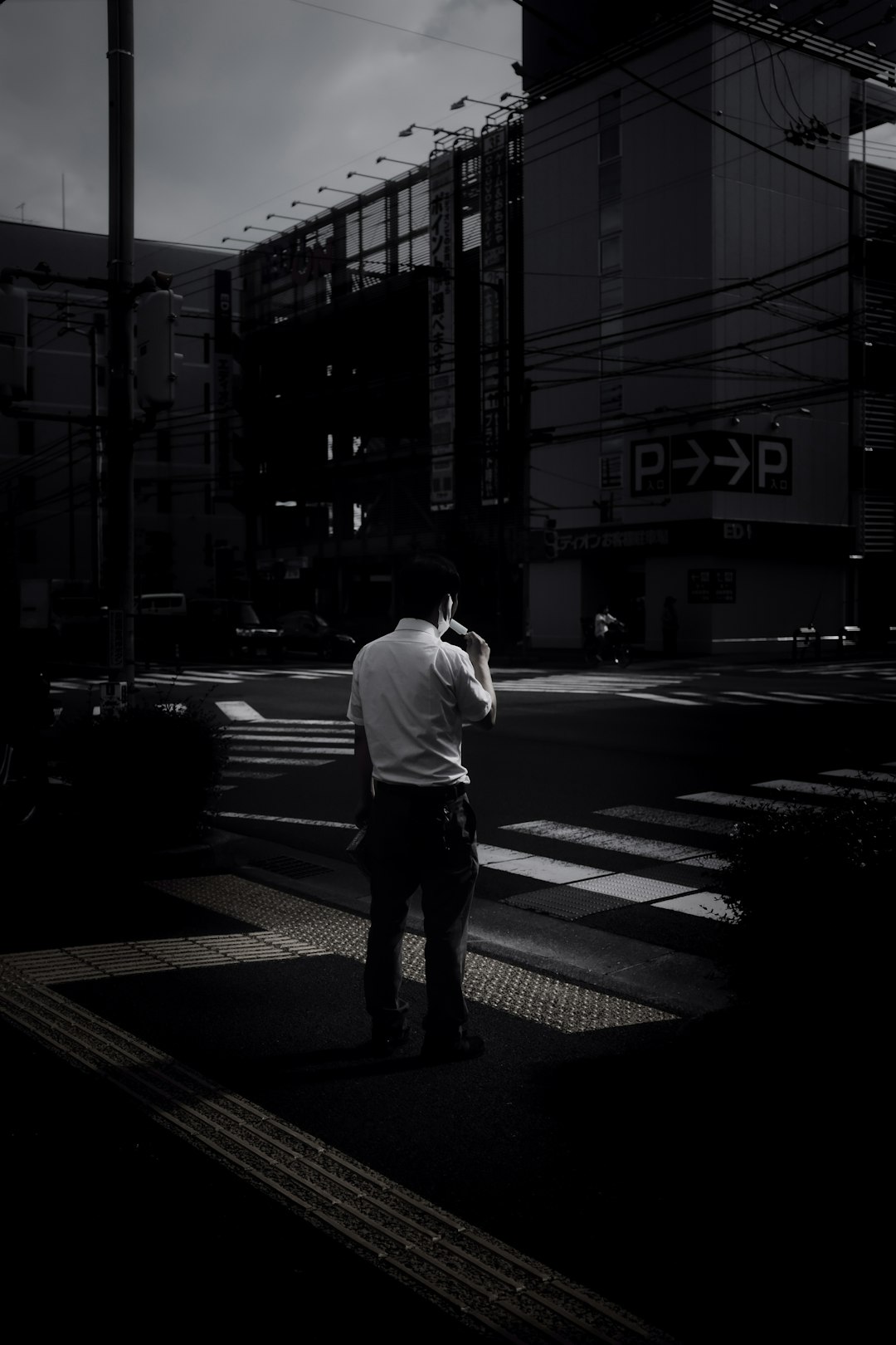 man in white dress shirt and black pants standing on pedestrian lane during night time