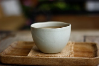Close-up of a beautifully crafted ceramic cup with antoas llc logo on a wooden table.