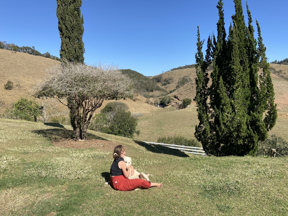 woman in red dress sitting on green grass field during daytime