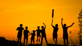 silhouette of people standing on grass field during sunset
